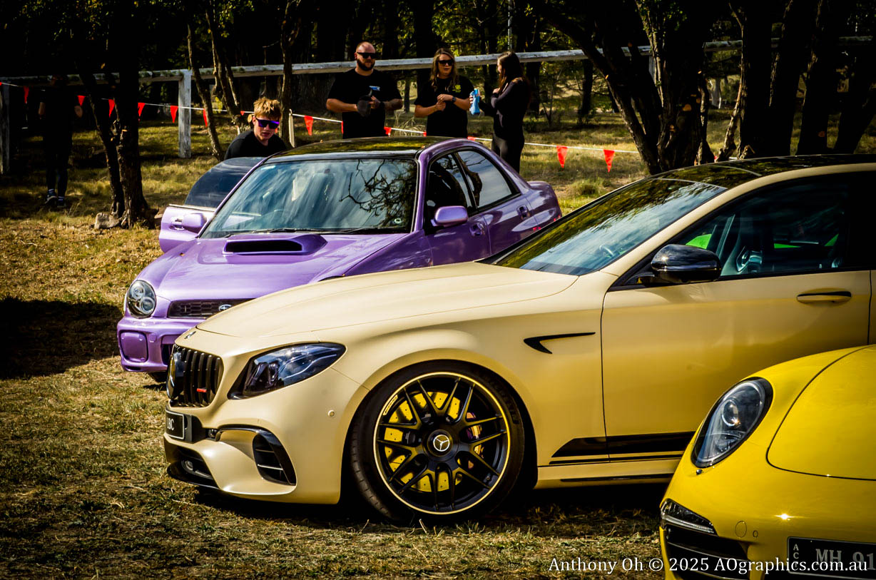 Three sporty cars in beige, purple, and yellow parked outdoors with people in the background.