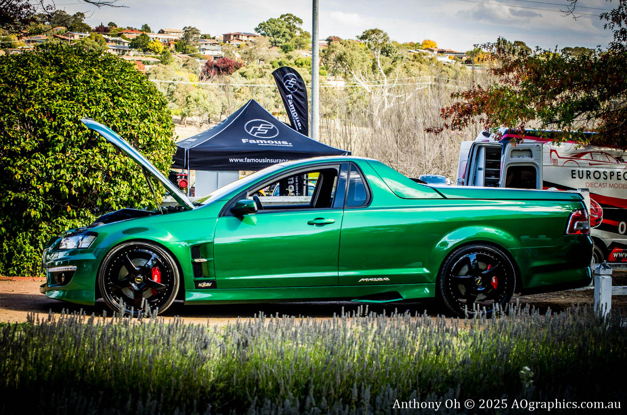 Green performance utility vehicle with hood open at an outdoor car show.