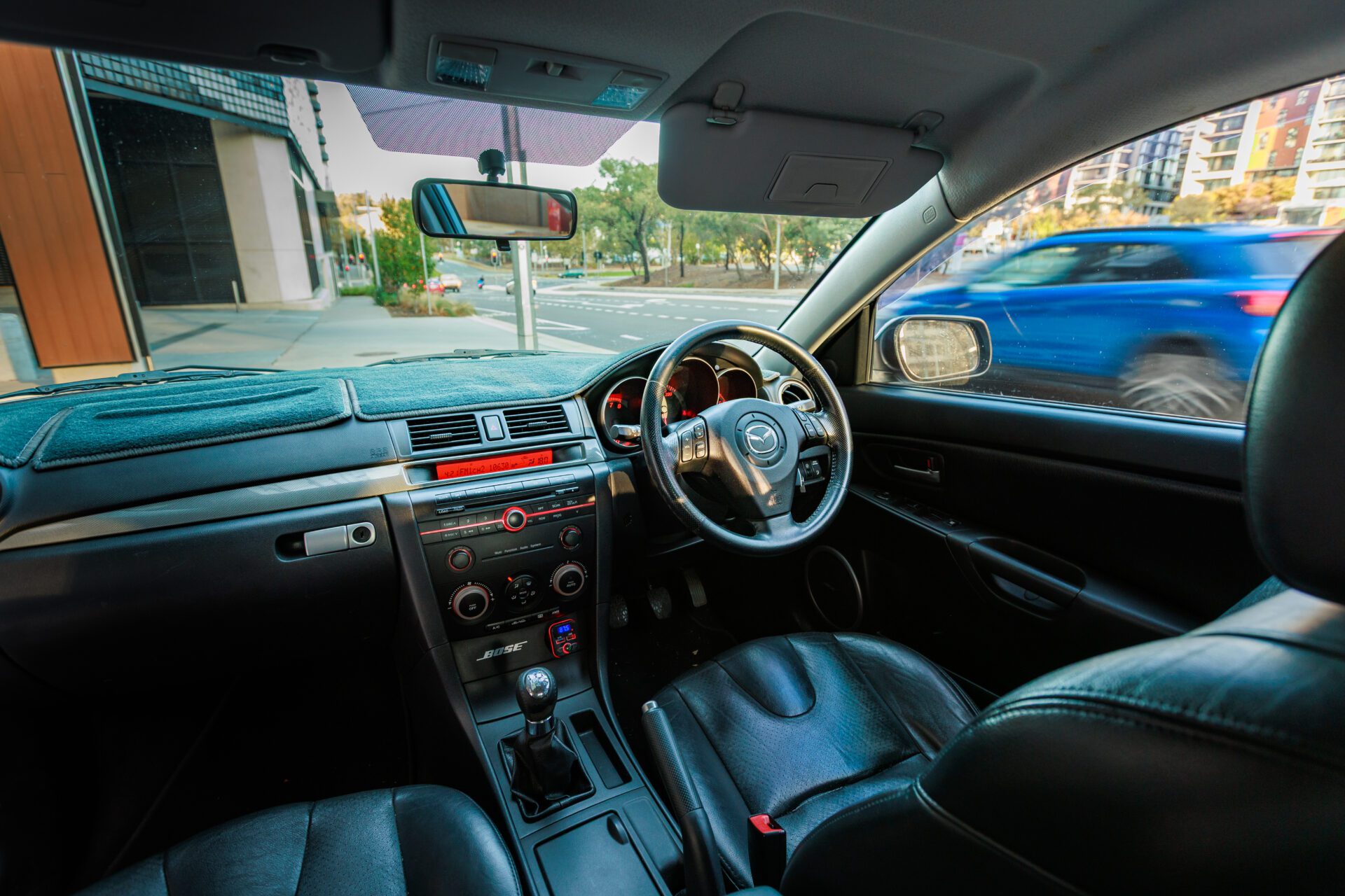 Interior view of a right-hand drive Mazda car with leather seats and a manual gear shift.